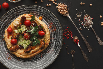 Hummus with vegetables and seafood on black background