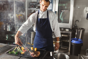 Chef cooking juicy beef steak at restaurant kitchen