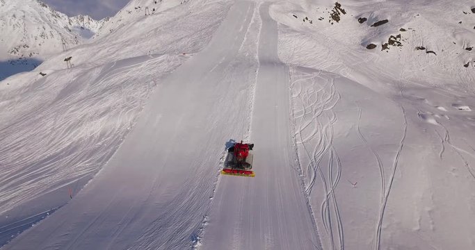 Aerial of snow groomer preparing a ski slope on an early winter morning