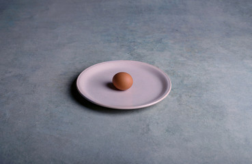 One fresh egg laying on plate 
