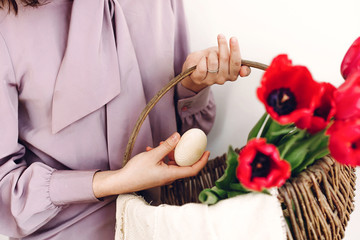 Obraz na płótnie Canvas easter hunt concept. beautiful stylish girl holding basket with pink tulips and natural easter eggs on white background isolated. happy child looking for egg. space for text
