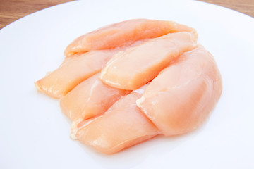 Raw chicken breasts and spices on white plate