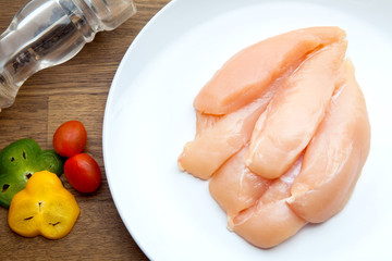 Raw chicken breasts and spices on white plate