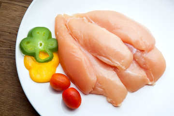 Raw chicken breasts and spices on white plate