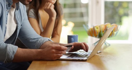 4K Happy couple shopping online at home, entering credit card details on laptop