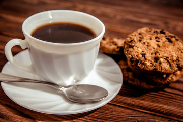 A cup of hot coffee stands on a wooden table 