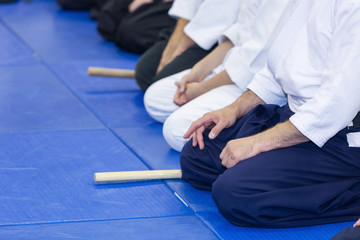 People in kimono sitting on tatami on martial arts weapon training