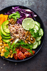 Buddha bowl dish with brown rice, avocado, pepper, tomato, cucumber, red cabbage, chickpea, fresh lettuce salad and walnuts. Healthy vegetarian eating, super food. Top view