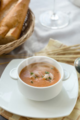 Vegetable cream soup with shrimps and croutons in white bowl close up