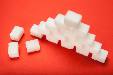 White sugar cubes on red background.