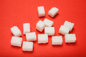 Spilled cubes of sugar on a red background.