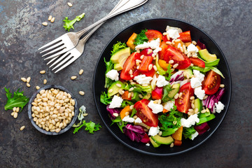 Vegetable dish, salad with avocado, pepper, tomato, italian mix, fresh lettuce, feta cheese and pine nuts. Healthy food. Top view