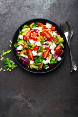 Vegetable dish, salad with avocado, pepper, tomato, italian mix, fresh lettuce, feta cheese and pine nuts. Healthy food. Top view