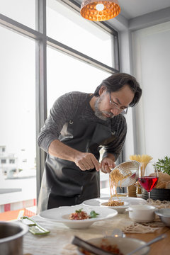 Handsome bearded cheef cook prepairing spaghetti on a kitchen, Chef cooks meal