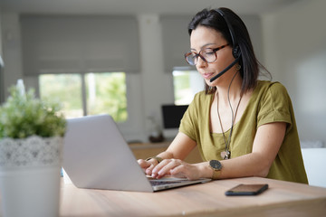 Teleoperator working in office with laptop and headset on