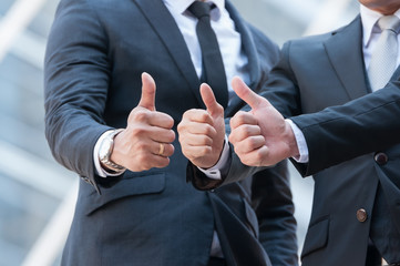 Unidentified business people show victory  sign by thumb up, body language to completed project.