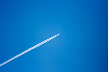 streak of an airplane flying in the clear blue sky - Powered by Adobe