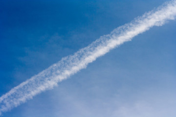 streak of an airplane flying in the clear blue sky