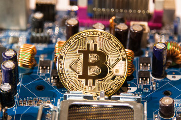 Gold coin with a gold bit of bitcoin on a background of microcircuits and computer spare parts