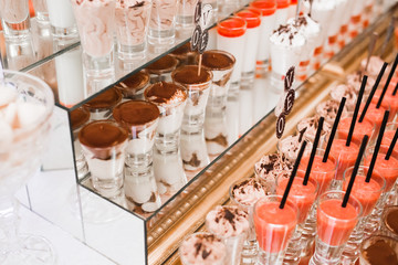 Delicious and tasty dessert table with cupcakes shots at reception closeup