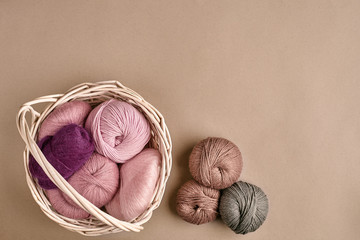 Balls of yarn and knitting needles. Colored yarn for knitting in a wicker bowl on a beige...