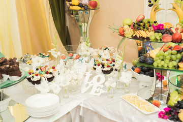 Delicious sweets on wedding candy buffet with desserts, cupcakes
