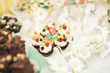 Delicious and tasty dessert table with cupcakes shots at reception closeup