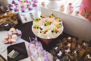 Delicious sweets on wedding candy buffet with desserts, cupcakes