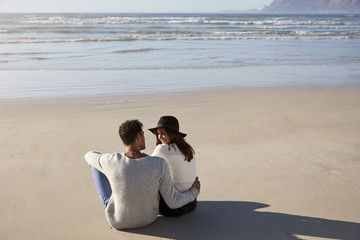 Fototapeta premium Romantic Couple Sitting On Winter Beach Together