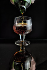 Cognac is poured from a bottle into glass