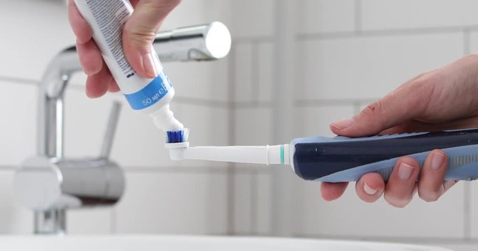 Toothpaste on electric toothbrush. White toothpaste applied on brush head.
