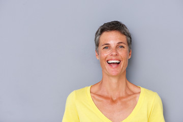 attractive older woman laughing by gray wall