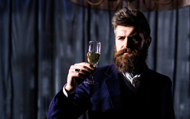 Bearded man with angry face holds champagne glass.