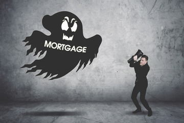 Terrifying businessman covering his face chased by a mortgage ghost
