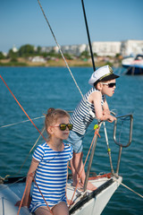 beautiful boy and girl in striped shirt and sunglasses on board white yacht in sea port