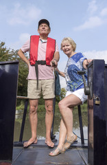 Couple on a holiday afloat steering a narrowboat using the tiller