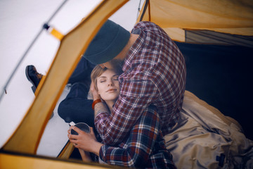 Fototapeta na wymiar Young couple hugs in tent during winter hike. Guy sits, girl lies on guy's knees.