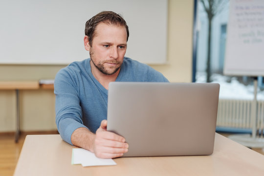 Engrossed businessman sitting reading his laptop