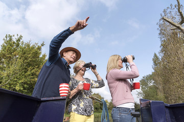 Group of people on a boating holiday using binoculars to spot wildlife along the Wilts & Berks...