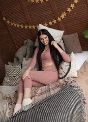 Fototapeta premium Smiling young woman sitting in bed and looks away