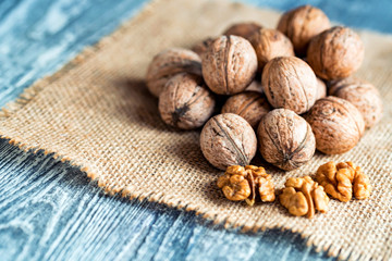 Walnuts and kernels on burlap on wooden backgound