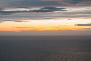 Fototapeta na wymiar Gray and orange clouds at sunset and gray sea