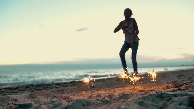 teenager girl with sparklers dancing on the beach. shot in slow motion