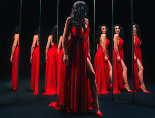 Portrait of beautiful brunette woman in red shoes and dress standing near the mirrors