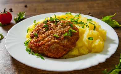 burger with mashed potatoes in white plate on wooden background