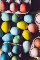 Packages with Dyed eggs for Easter holidays, colored  with red,blue,green,yellow  and pink tint inside package are set over a wooden  background