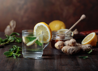 Ginger tea with honey , lemon and mint on old wooden table .