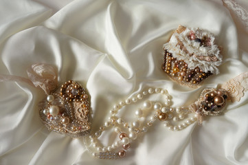 Textile wedding background with Hand Made Bridal Jewelry. Brooch Cake, Heart Necklace. Silk, pearl and bohemian glass accents wedding accessory.