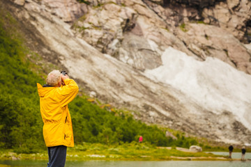 Naklejka na ściany i meble Tourist taking photo in norwegian mountains
