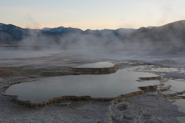 Waterfilled limestone terraces at Mammoth Hot Springs at dawn when the early morning fog is still present